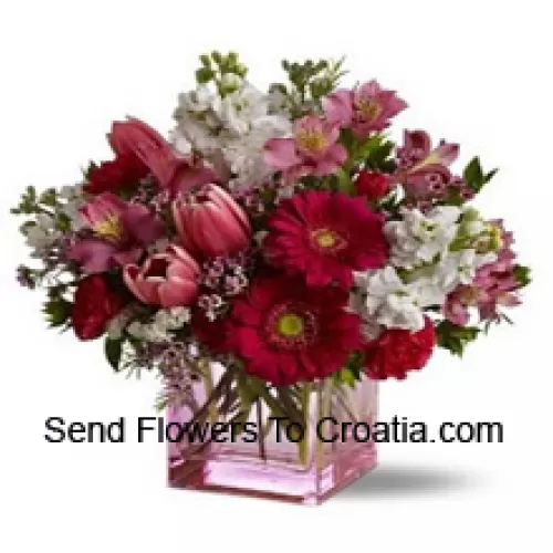 Roses rouges, tulipes rouges et fleurs assorties avec des garnitures saisonnières arrangées magnifiquement dans un vase en verre