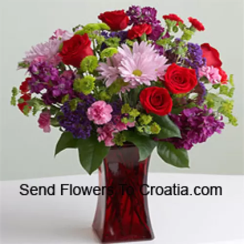 Roses rouges, oeillets roses et autres fleurs saisonnières assorties dans un vase en verre