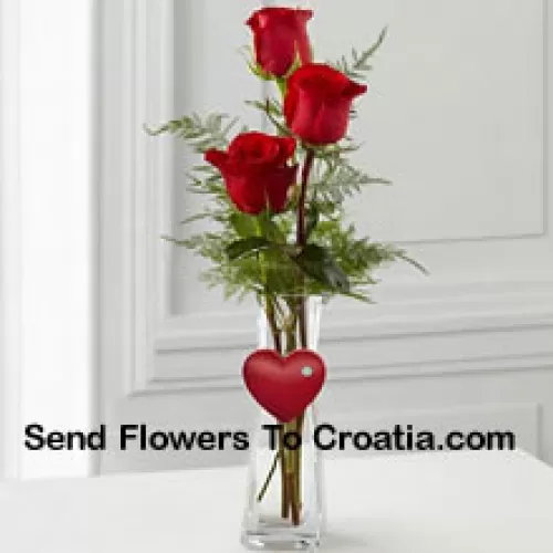 3 roses rouges dans un vase en verre avec un petit cœur attaché
